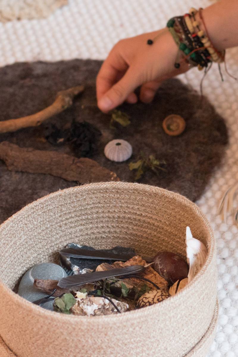 Hand greift in eine runde Schachtel mit Steinen