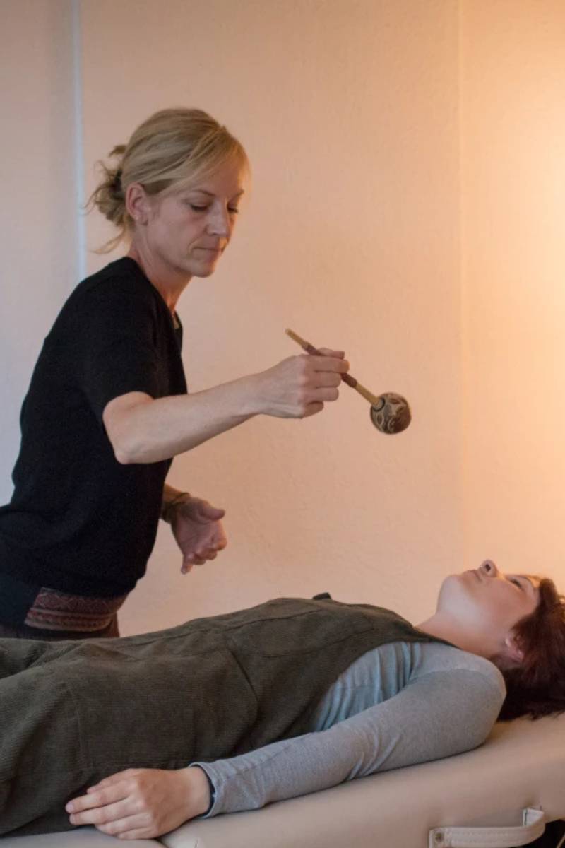 Miriam Schulz mit Rassel bei der schamanischen Behandlung einer liegenden Frau
