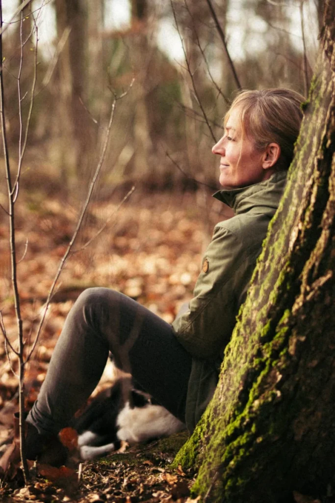 Miriam Schulz sitzt am Waldboden an einen Baum gelehnt